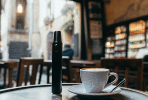 A starter vape kit for use abroad A sleek, minimalist vape resting on a table in a quaint European café, next to a cup of coffee.