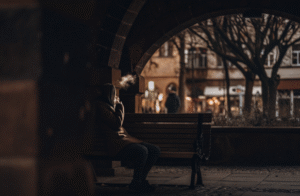 A discreet and simple vape for new users A person discreetly using a small, simple vape while sitting on a park bench in a foreign city.